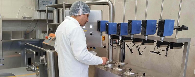 一位穿着白色实验服的食品科学家在实验室里用机器工作。